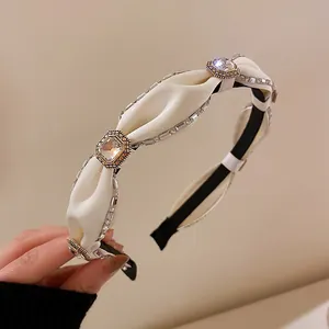 Nahaufnahme eines gepolsterten weißen Stirnbands mit elegantem Strasssteinbesatz.
