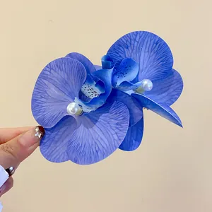 Macro view of blue fabric orchid hair clip featuring an elegant pearl center detail