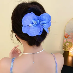 Detailed view of a blue orchid hair clip with pearls worn on a bun, elegant style.