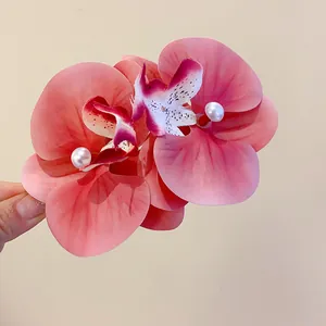 Close-up detail of a pink fabric orchid hair clip featuring elegant faux pearl centers
