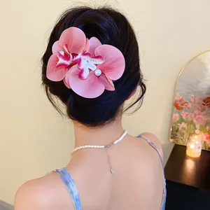 Elegant pink fabric orchid flower hair clip with pearl detail shown on model's hair.