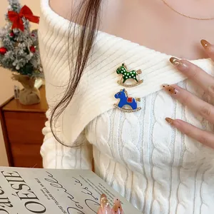 Elegant close-up of enamel rocking horse brooches with rhinestones on a white sweater