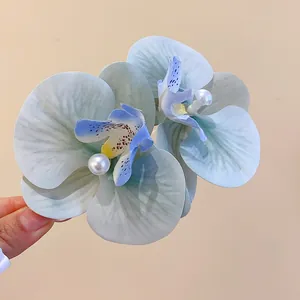 Detailed view of fabric orchid hair clip with pearl center, blue and green gradient.