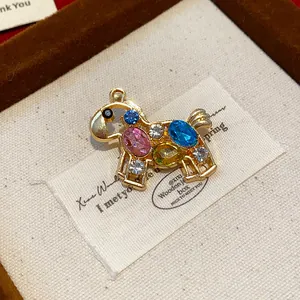 Detailed close-up of a golden horse brooch with colorful rhinestones in a gift box