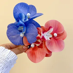 Close-up of orchid fabric hair clips with pearl details in blue and coral