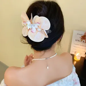 Close-up of elegant fabric orchid hair clip with pearls worn by model