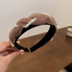 Detailansicht eines eleganten braunen Gaze-Schwammstirnbands mit zarten Perlenverzierungen
