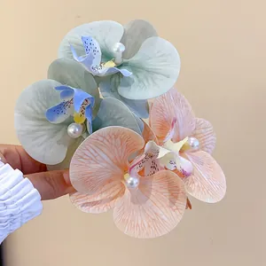 Close-up of elegant orchid fabric hair clips with central pearl detailing.