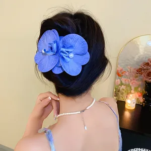 Elegant blue fabric orchid hair clip with small pearl accents worn on a model's bun