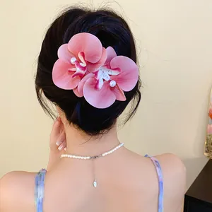 Back view of a pink orchid fabric hair clip with pearl detail on brunette hair