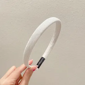 Nahaufnahme eines minimalistischen, cremefarbenen, stoffbezogenen Schwamm-Haarreifens