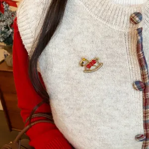 Rocking horse brooch with red enamel and crystals pinned on a white knitted vest.