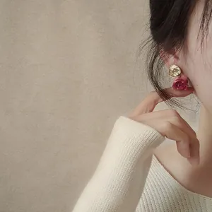 Elegant handmade dried rose earrings with gold metal disc worn by an Asian model