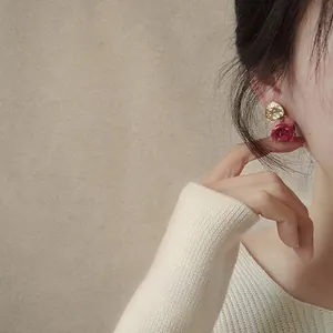 Close-up of elegant dried rosebud earrings worn by a model in a lifestyle setting