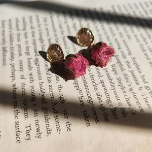 Detailed macro view of handmade dried pink rose earrings with hammered gold studs