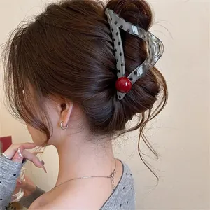 Detail view of a large vintage hair claw clip with polka dots and red accent on model