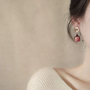 Close-up of elegant gold earrings with pink eternal rose flower bud drops.