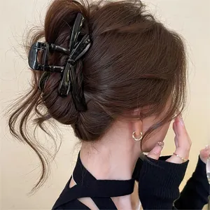 Close-up of a large black bow hair claw clip used to secure a messy bun hairstyle