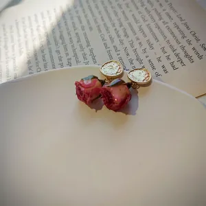 Close-up of elegant dried rose earrings featuring textured gold studs on white plate.