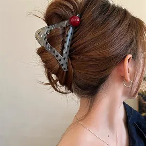 Macro view of a stylish leopard pattern hair claw clip with a red bead on brown hair