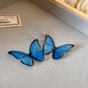 Vista detallada de elegantes pendientes de mariposa azul con alas translúcidas