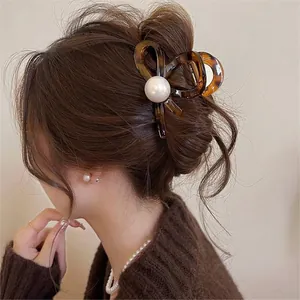 Close-up of elegant tortoise brown bow hair claw clip with a large pearl decoration