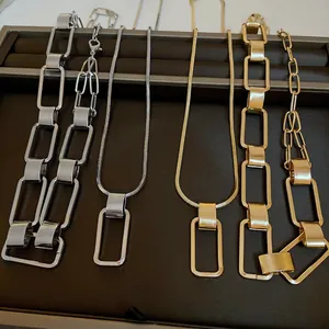 Primo piano di collane geometriche in oro e argento su un vassoio per gioielli