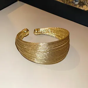 Close-up of a luxurious gold-plated multi-strand open cuff bracelet with fine textures