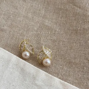 Detailed shot of gold-plated leaf earrings with zircons and champagne pearls