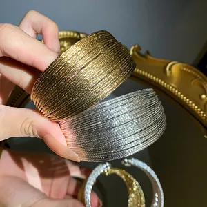 Detail of gold and silver plated multilayer open bangles with a textured metallic finish.