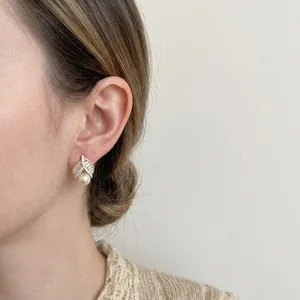 Detail view of elegant French gold leaf earrings with pearls and cubic zirconia on a model.