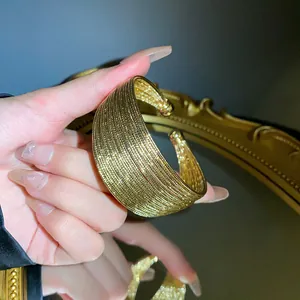 Detailed close-up of a multi-layered gold-plated open bangle with elegant shiny textures