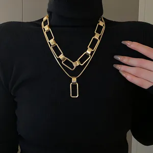 Dettaglio ravvicinato di una collana dorata a maglie rettangolari su un maglione nero