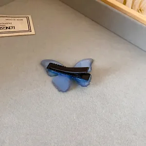 Vista detallada de una pinza para el cabello de mariposa azul traslúcida con clip