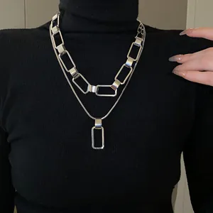 Dettaglio ravvicinato della collana geometrica argentata a doppio strato con maglie rettangolari