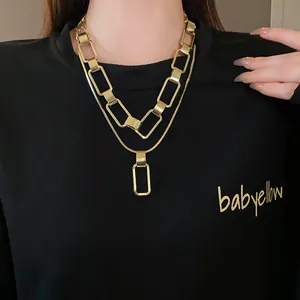 Primo piano di una collana a catena rettangolare geometrica dorata a strati su felpa nera
