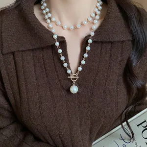 Primo piano di una collana di perle a strati con chiusura a T vintage e pendente.