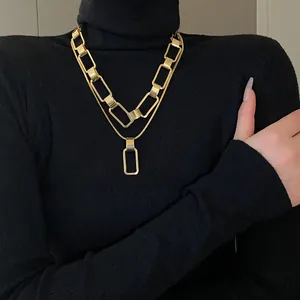 Dettaglio della collana a doppio strato con catena rettangolare dorata su maglione nero