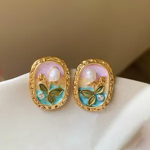 Close-up of vintage oval stud earrings featuring pearl flower and colorful enamel detail
