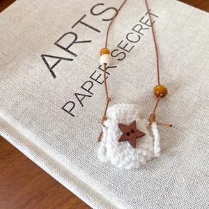 Close-up of cream crocheted mini bag pendant with wooden star button detail