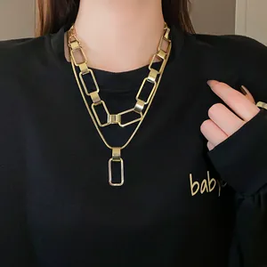 Primo piano di una collana a due strati con maglie rettangolari dorate indossata.