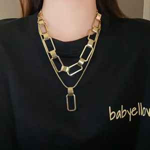 Primo piano di una collana a catena rettangolare dorata a due strati su maglia nera
