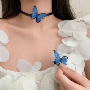 Vista detallada de gargantilla de mariposa azul y clip en modelo con vestido blanco