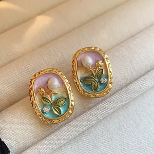 Close-up detail of elegant enamel flower earrings with pearls and rhinestones