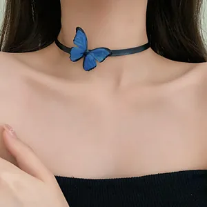 Primer plano de un delicado dije de mariposa azul en un collar choker de cinta negra