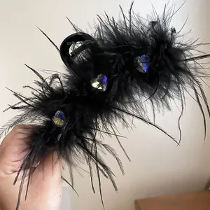 Close-up of elegant black feather hair claw clip with heart rhinestones