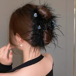 Detailed view of an elegant black feather hair claw clip with rhinestone heart accents.