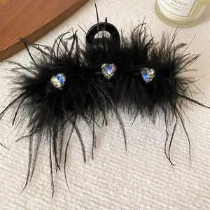 Close-up detail of a black feather hair claw clip with sparkling heart-shaped rhinestones