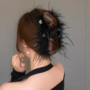 Close-up of black feather hair claw clip with heart-shaped rhinestones on hair bun