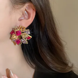 Primo piano di eleganti orecchini a lobo oversize a forma di fiore con strass quadrati.